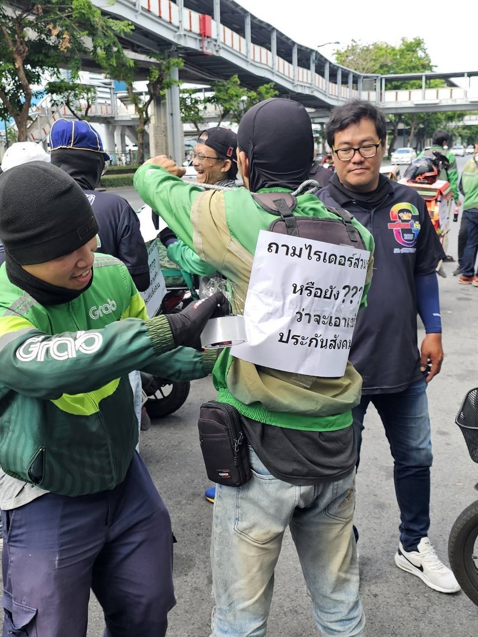ไรเดอร์ Grab ช่วยกันติดป้ายประท้วงประกันสังคมบังคับ